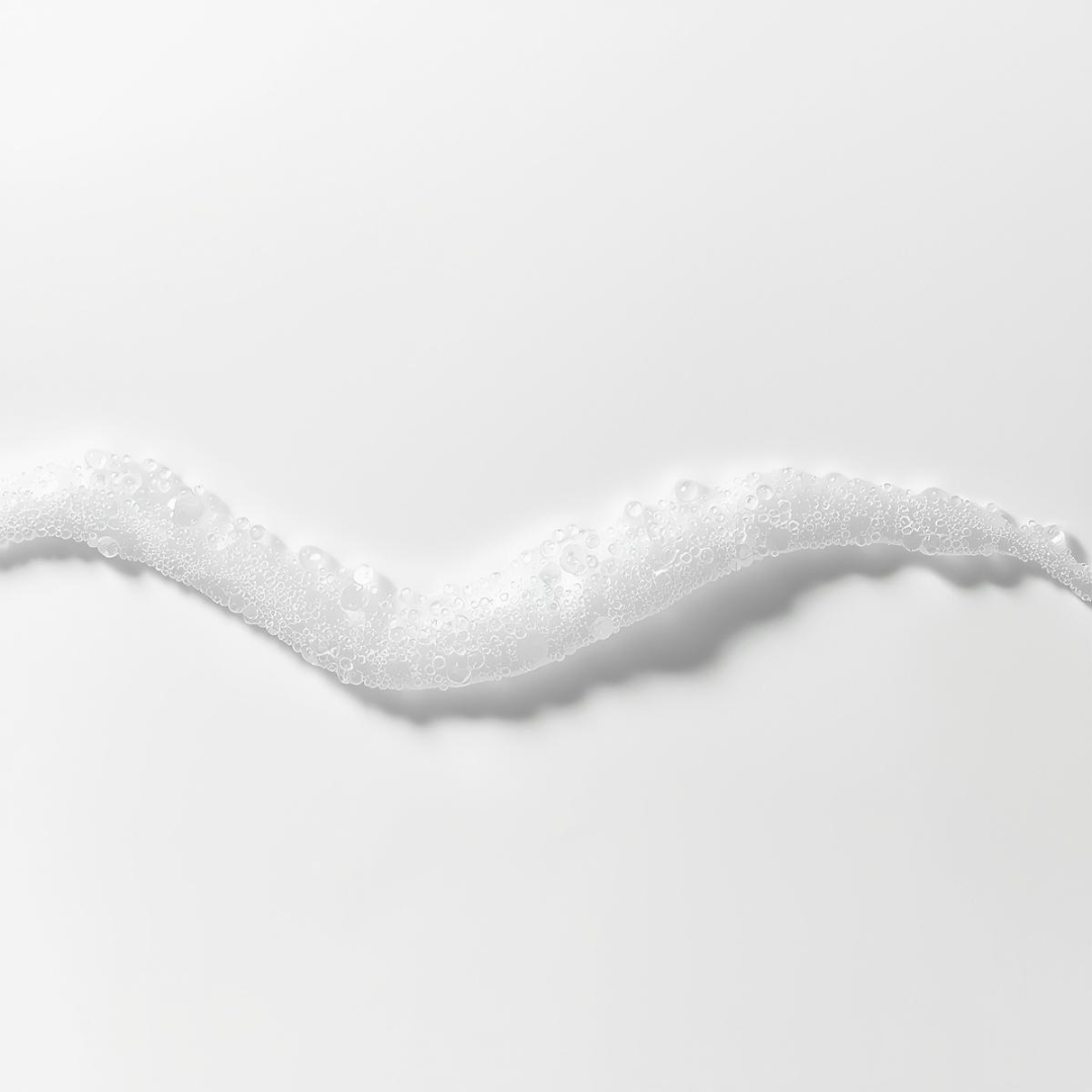 Textura de espuma cosmética sobre agua en fondo blanco, con estética minimalista y premium, representando el cuidado suave de la piel en Urban Natur
